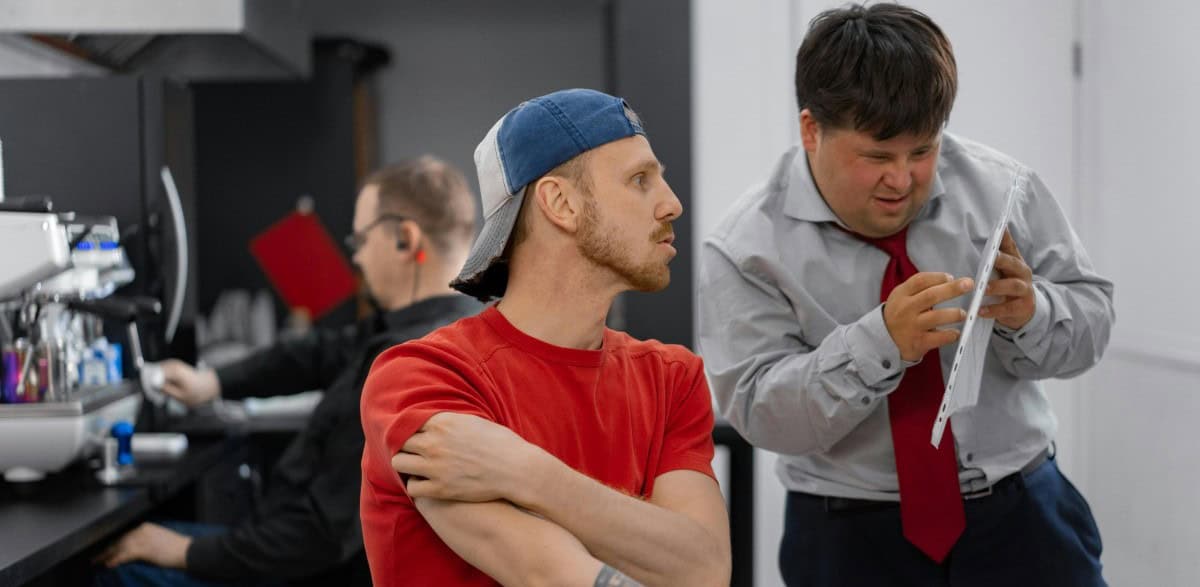 Mensch mit Down Syndrom im Gespräch mit Kollegen.